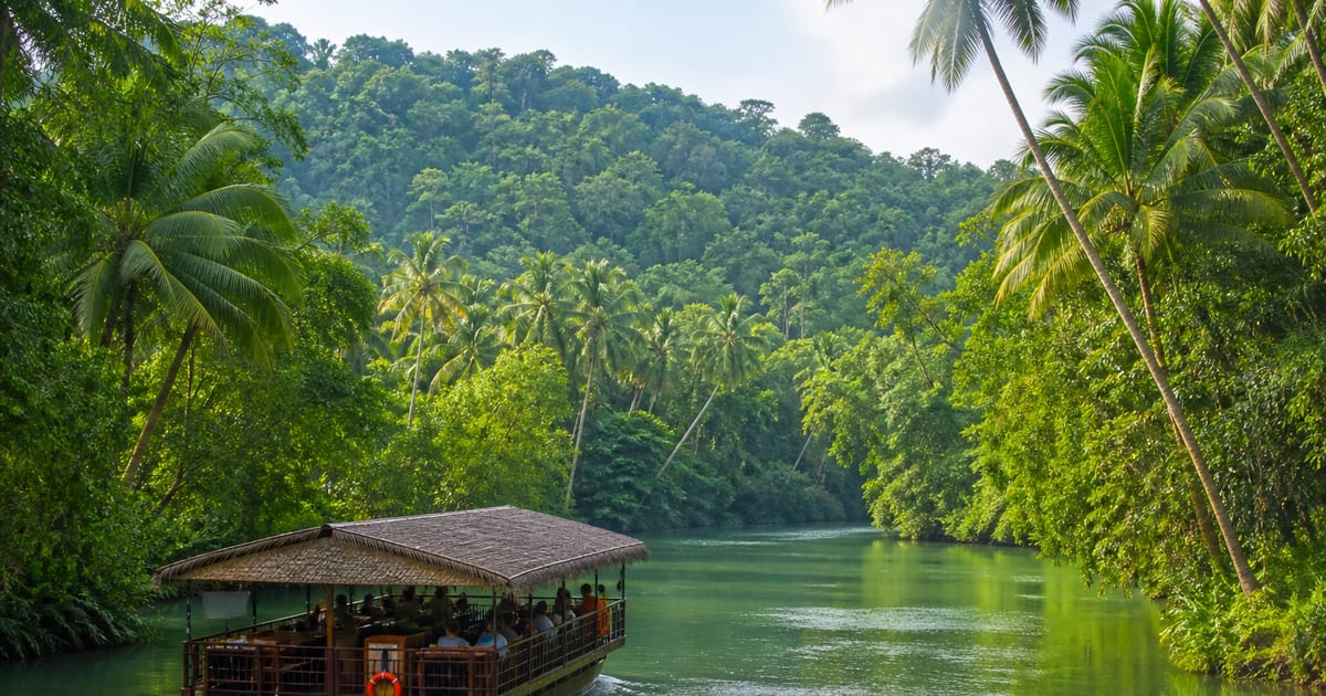 Floating restaurant boat cruising between tropical banks on the Loboc River